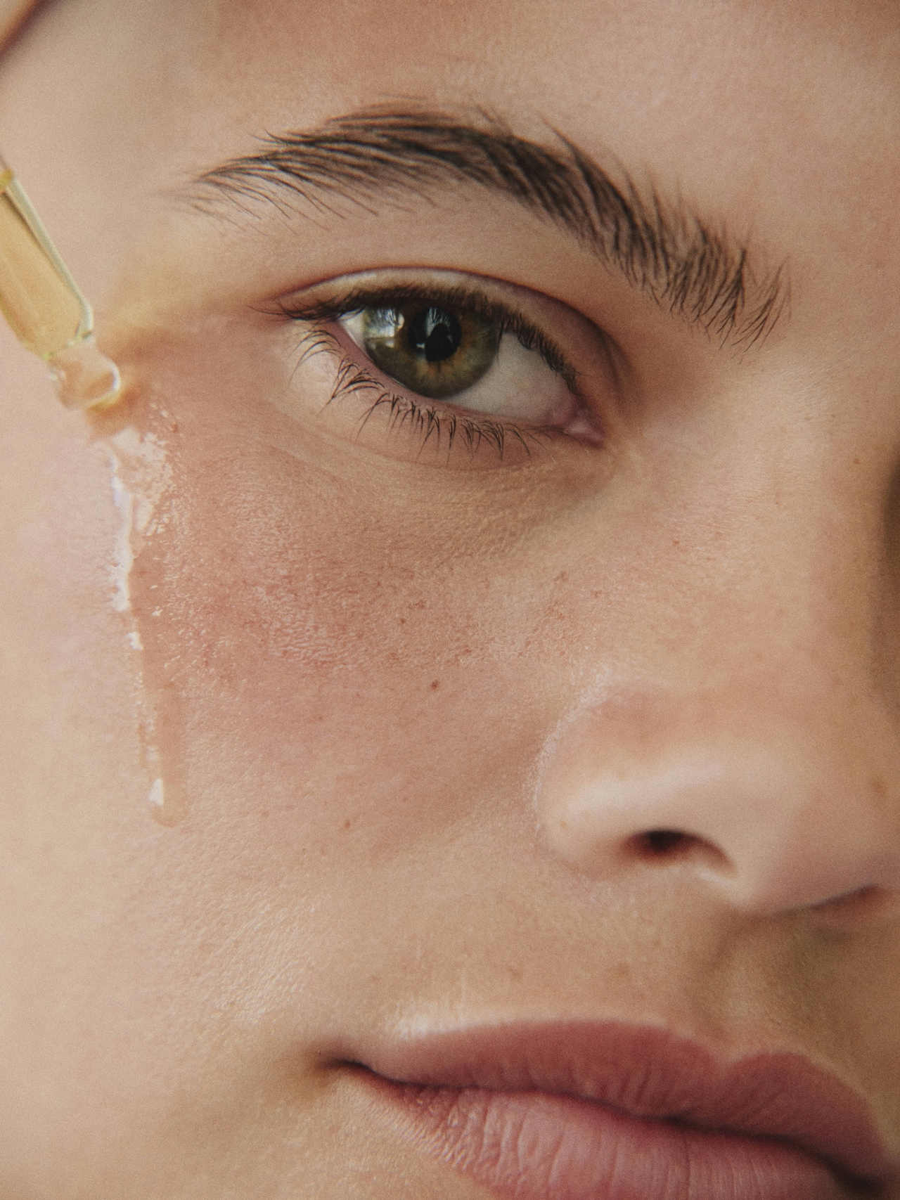 Close-up of a skincare serum dropper against fresh skin